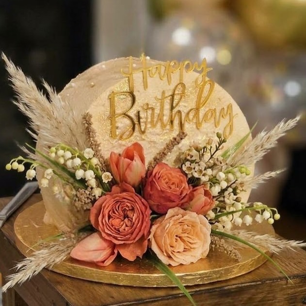 A boho cake with fresh roses, pampas grass and a gold Happy Birthday topper